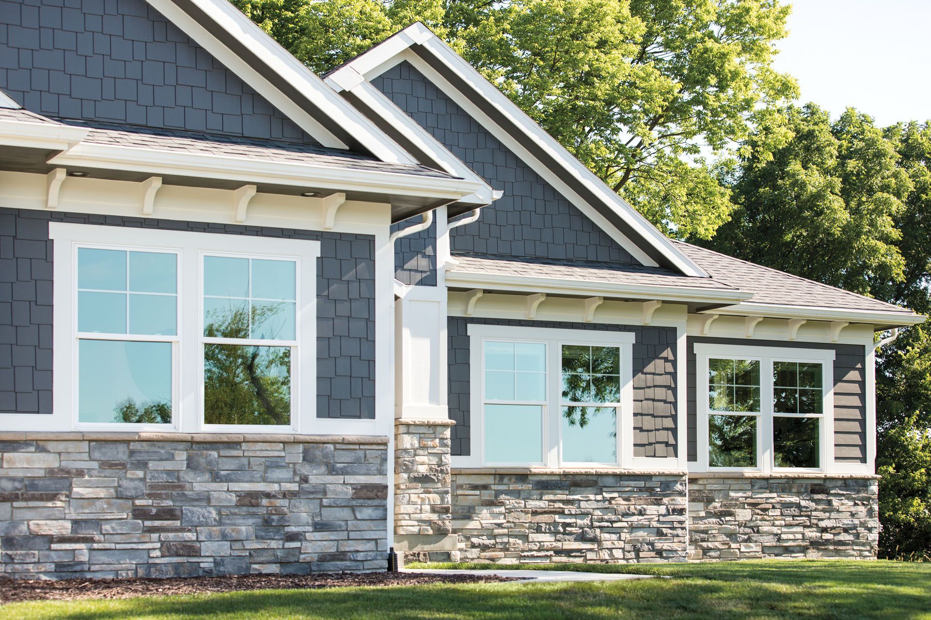 House exterior with stone facade, blue siding, white trim, and multiple windows.